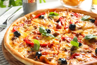 Delicious pizza with olives and sausages on table