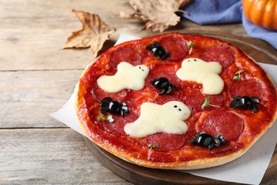 Photo of Cute Halloween pizza with ghosts and spiders served on wooden table