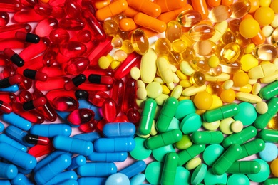Photo of Heap of different colorful pills as background, top view