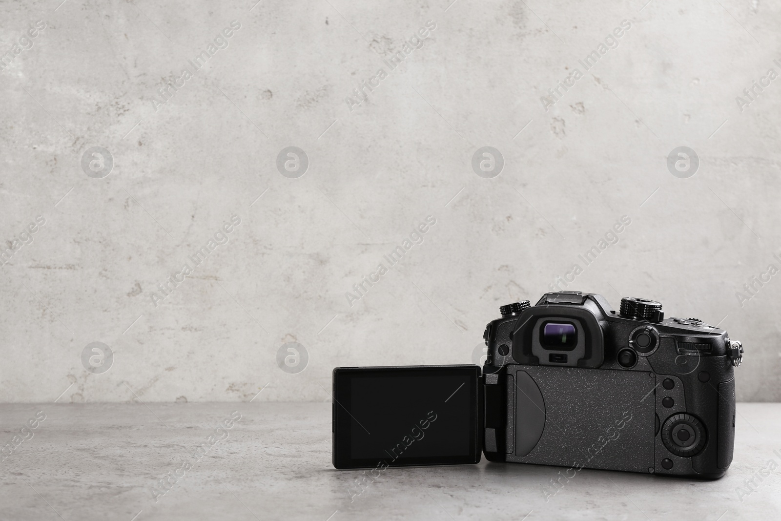 Photo of Modern camera on light grey stone table, space for text. Video production industry