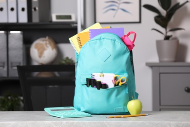Photo of Turquoise backpack and different school stationery on table indoors