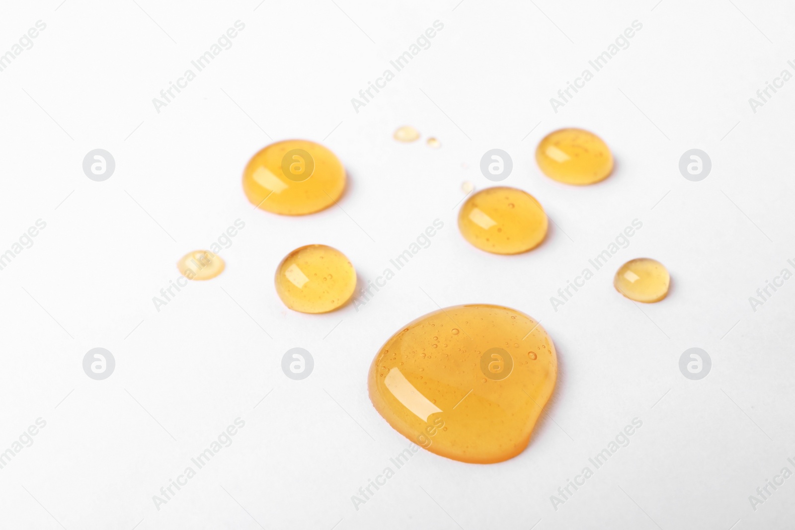 Photo of Drops of sweet honey on white background