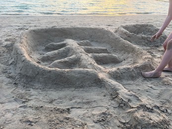 Photo of Child near palm tree made of sand outdoors, closeup