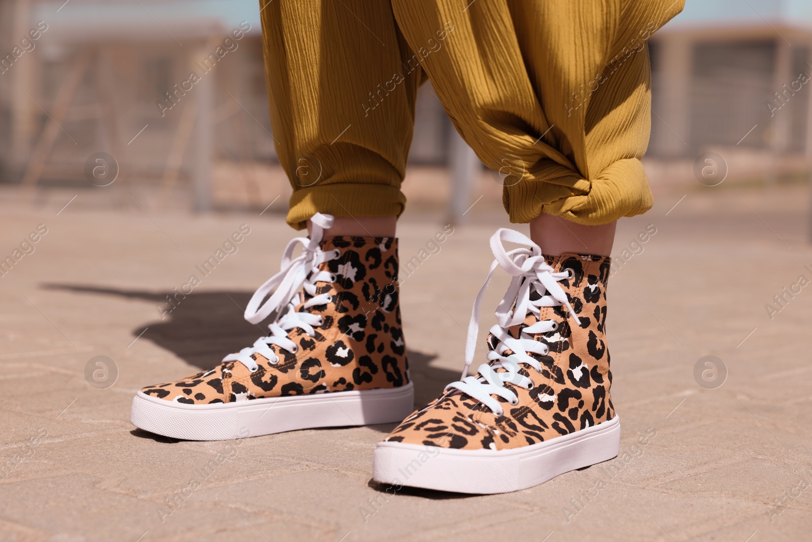 Photo of Woman wearing sneakers with leopard print outdoors, closeup