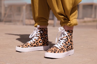 Woman wearing sneakers with leopard print outdoors, closeup