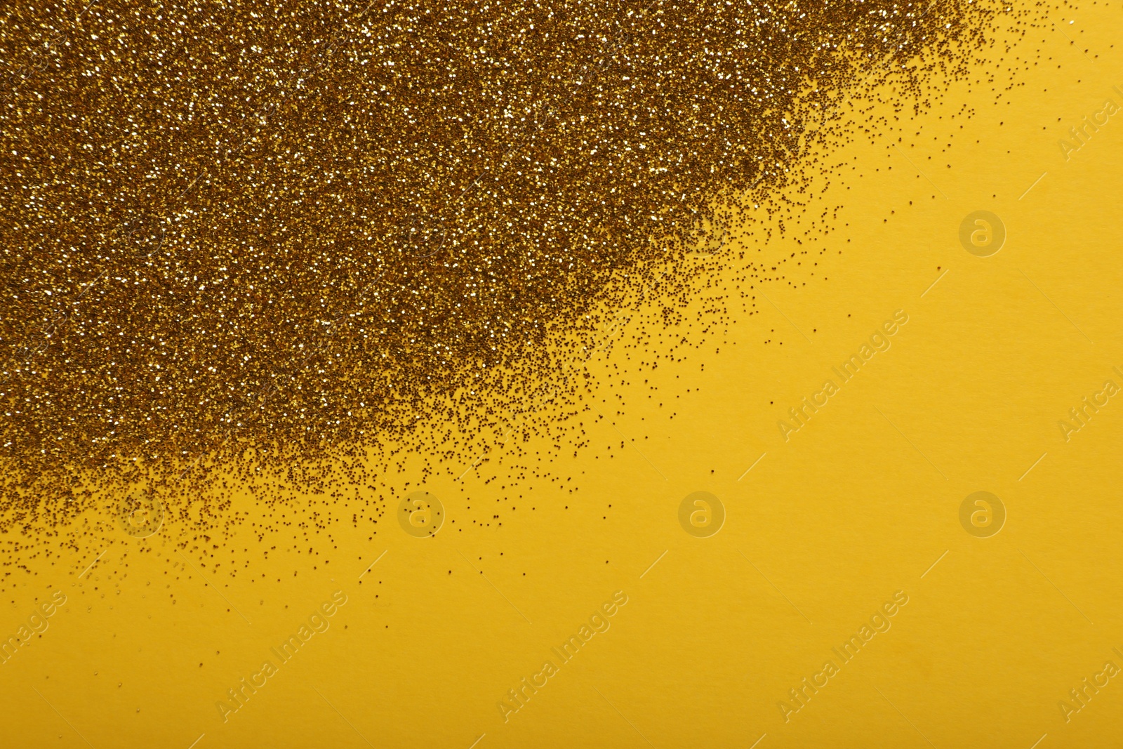 Photo of Shiny golden glitter on yellow background, top view. Space for text