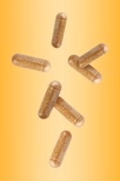 Vitamin. Capsules falling on orange gradient background