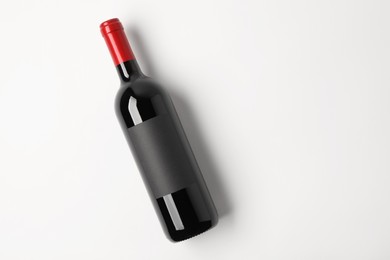 Bottle of tasty red wine on white background, top view. Space for text