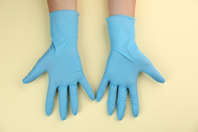 Person in medical gloves on beige background, top view