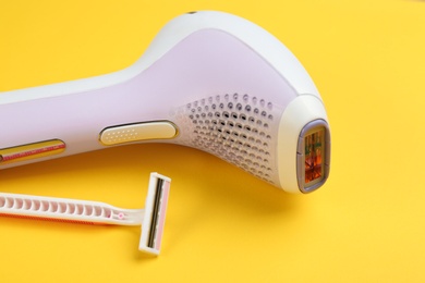 Image of Modern photoepilator and shaving razor on yellow background
