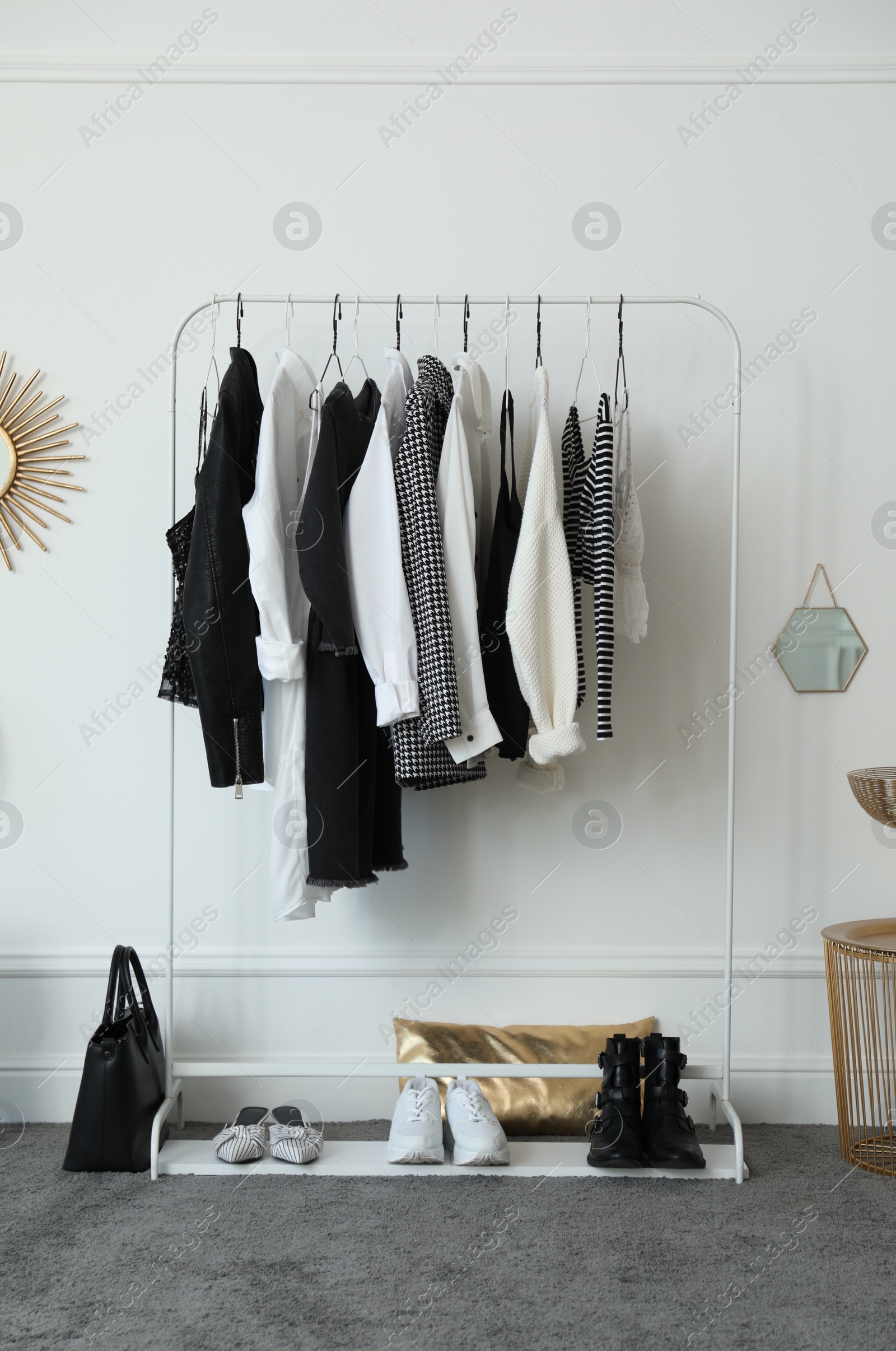 Photo of Rack with stylish clothes near white wall in dressing room