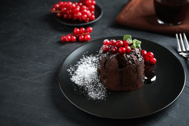 Photo of Delicious warm chocolate lava cake with mint and berries on dark grey table