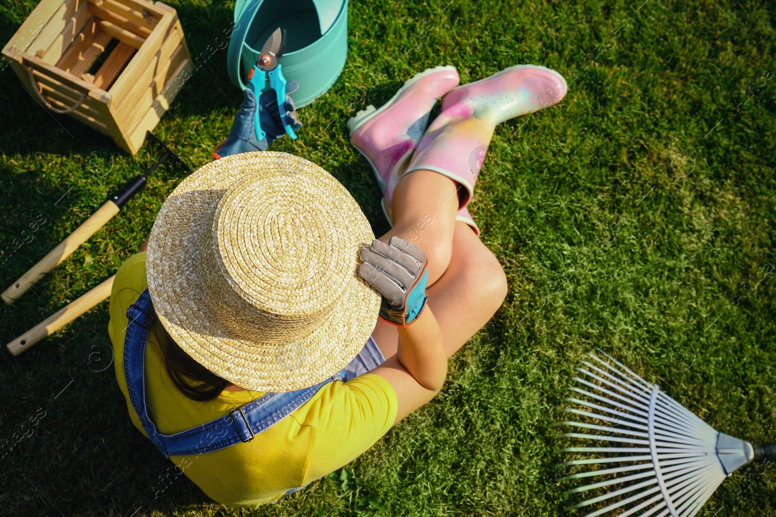 Photo of Young woman and gardening tools on green grass, above view