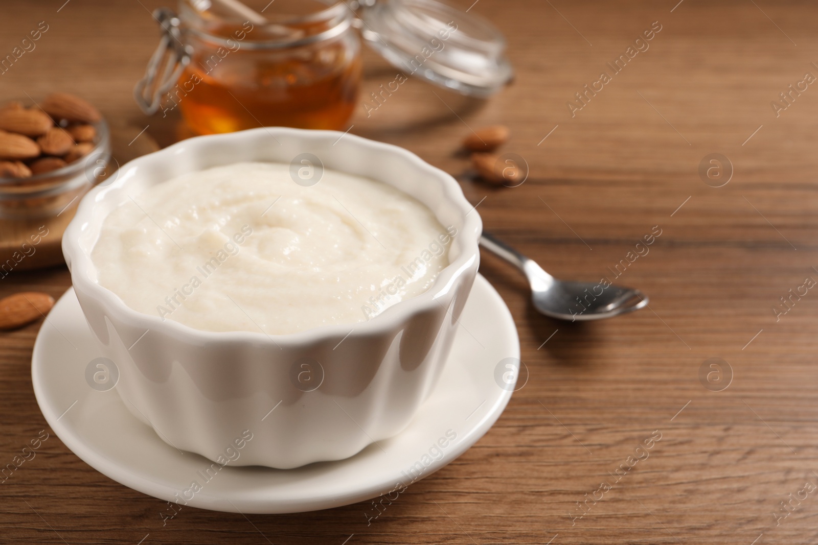 Photo of Bowl with delicious semolina pudding on wooden table, space for text