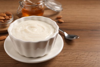 Photo of Bowl with delicious semolina pudding on wooden table, space for text