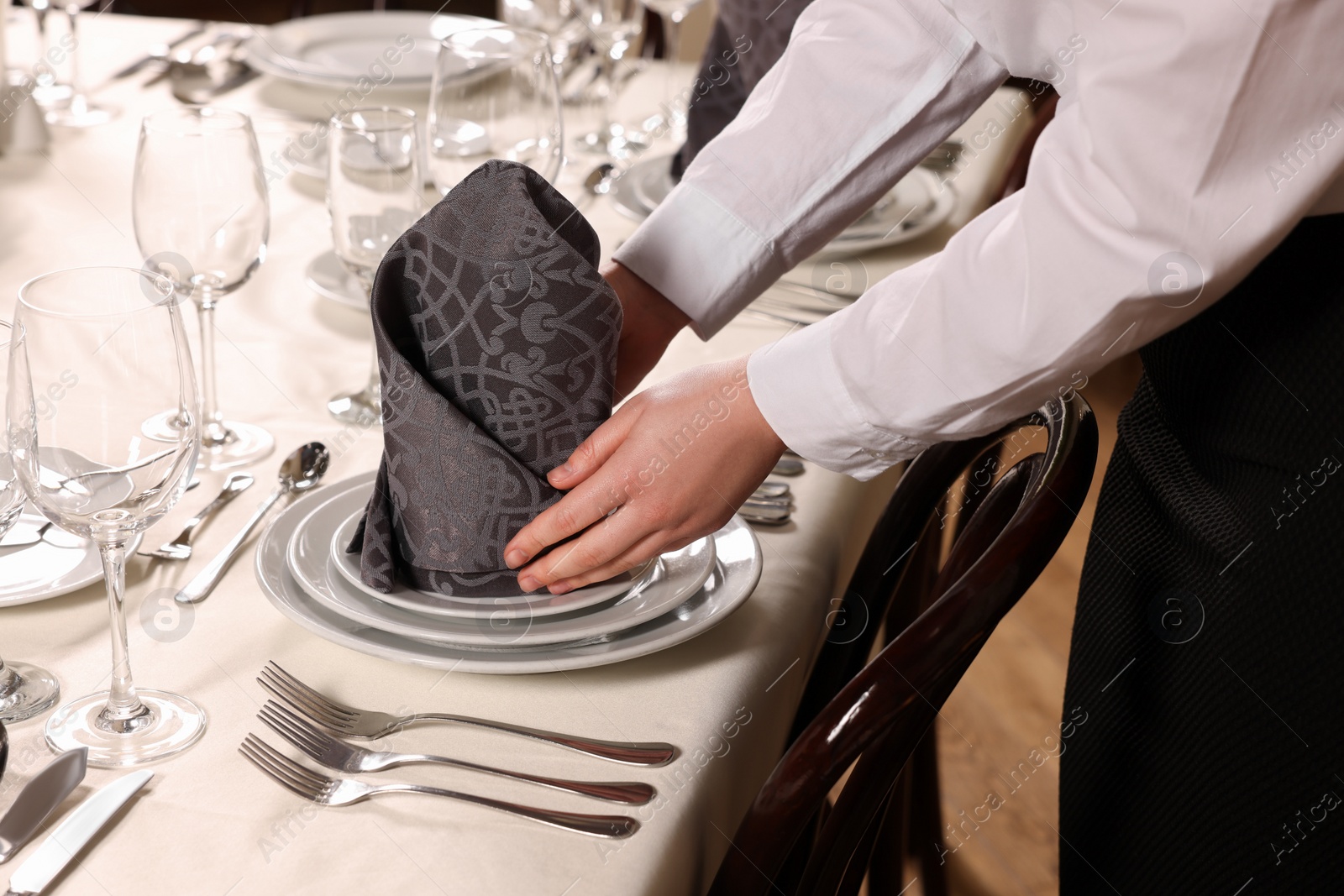 Photo of Woman setting table in restaurant, closeup. Professional butler courses