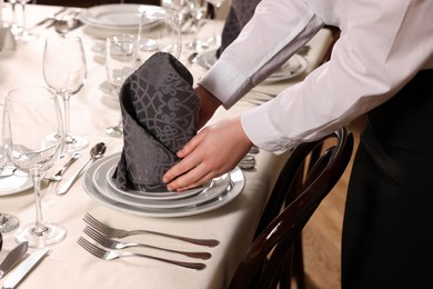 Woman setting table in restaurant, closeup. Professional butler courses