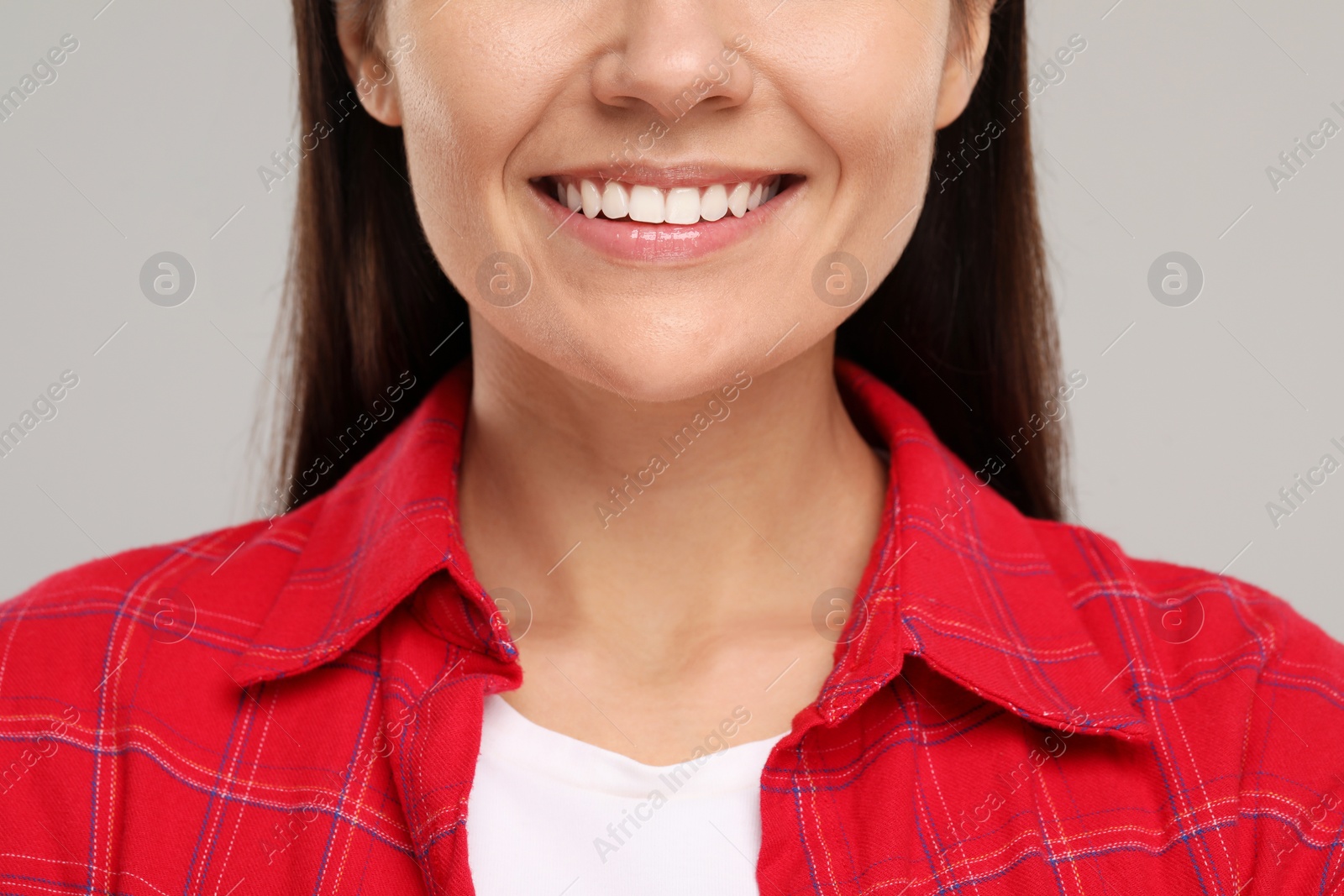 Photo of Young woman with clean teeth smiling on light grey background, closeup