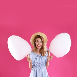 Photo of Happy young woman with cotton candies on pink background