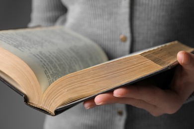 Photo of Woman reading Bible against grey background, closeup