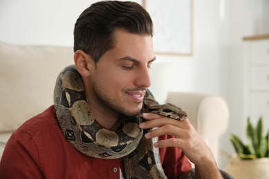 Photo of Man with his boa constrictor at home. Exotic pet