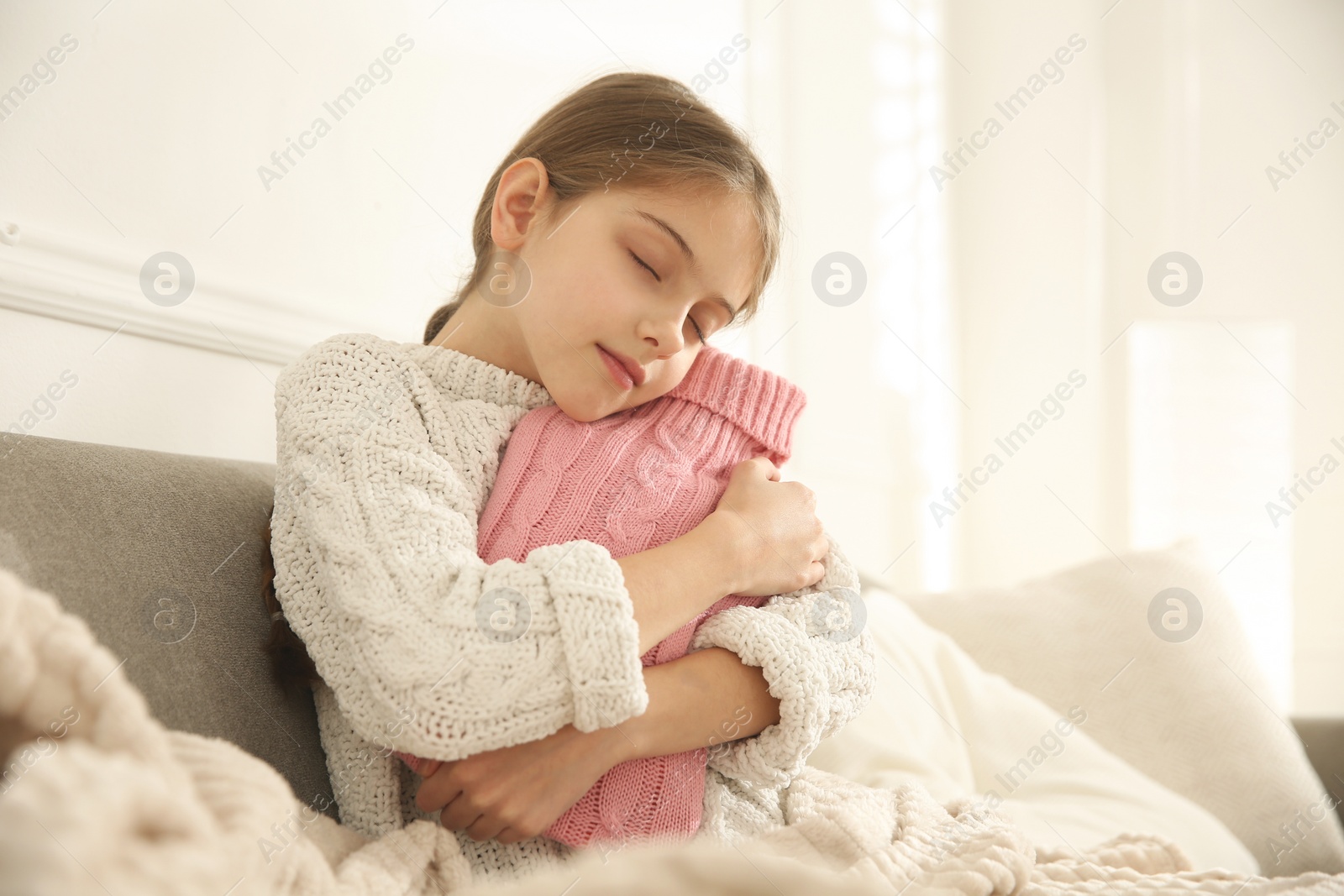 Photo of Ill girl with hot water bottle suffering from cold at home