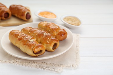 Photo of Delicious sausage rolls on white wooden table. Space for text