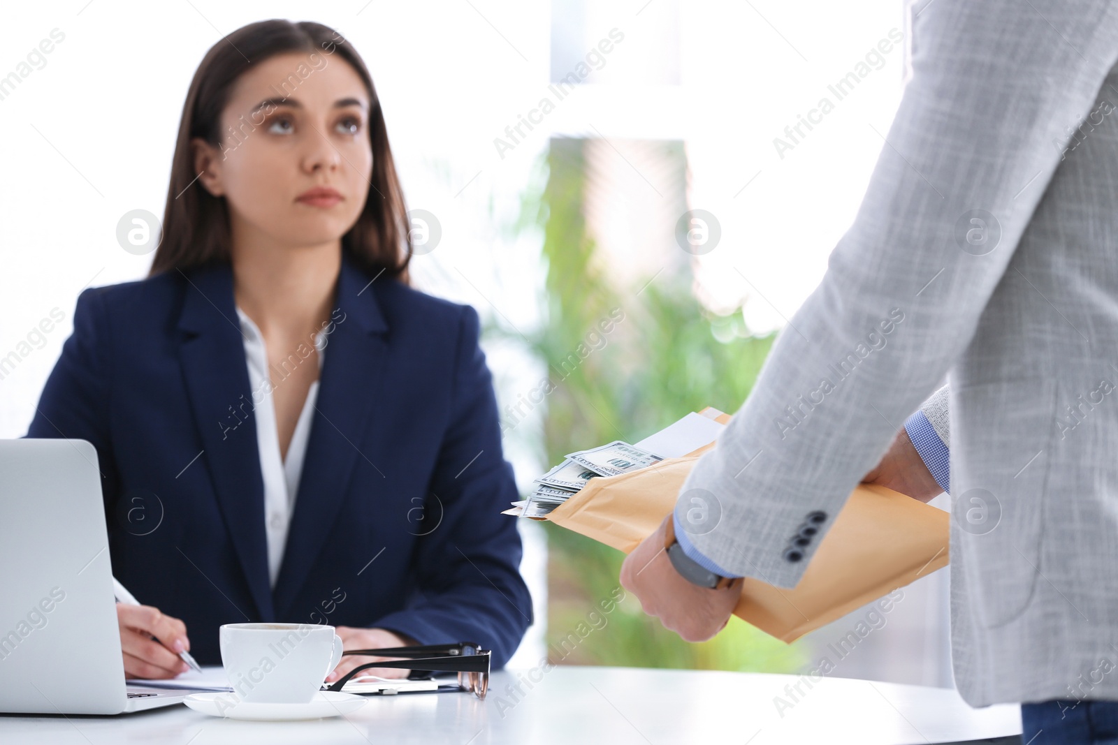 Photo of Man offering bribe to businesswoman at table in office