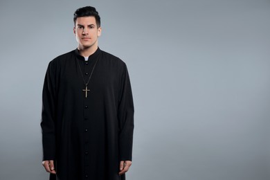 Photo of Priest wearing cassock with clerical collar on grey background. Space for text