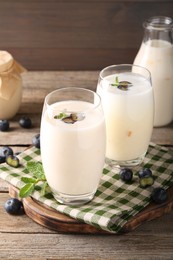 Photo of Tasty yogurt in glasses and blueberries on wooden table, closeup