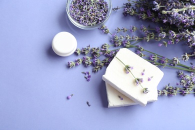 Photo of Flat lay composition with hand made soap bars and lavender flowers on violet background, space for text