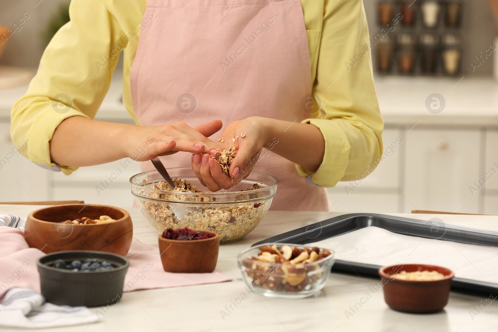 Photo of Woman making granola at table in kitchen, closeup