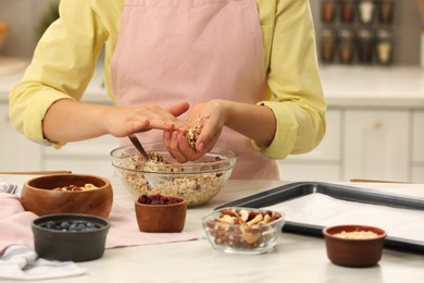 Photo of Woman making granola at table in kitchen, closeup