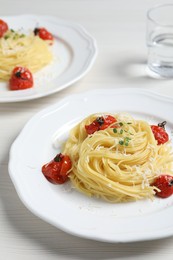 Photo of Tasty capellini with tomatoes and cheese served on white wooden table, closeup. Exquisite presentation of pasta dish
