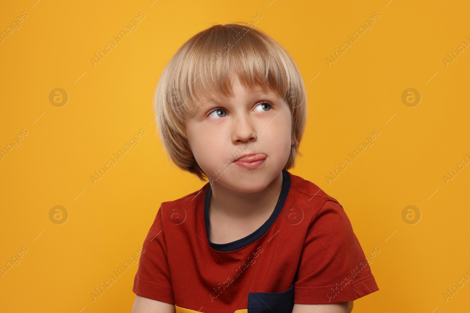 Photo of Cute boy showing his tongue on orange background