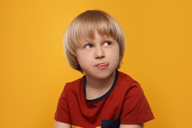 Cute boy showing his tongue on orange background