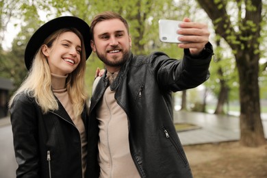 Photo of Lovely couple with smartphone taking selfie on spring day
