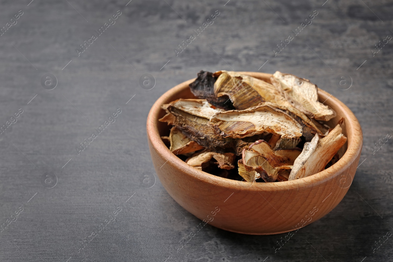 Photo of Bowl of dried mushrooms on color background. Space for text