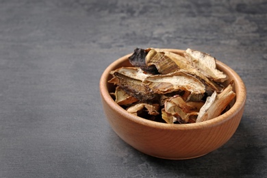 Bowl of dried mushrooms on color background. Space for text