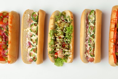 Photo of Delicious hot dogs with different toppings on white background, flat lay