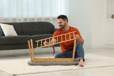 Photo of Man assembling shoe storage bench on floor at home