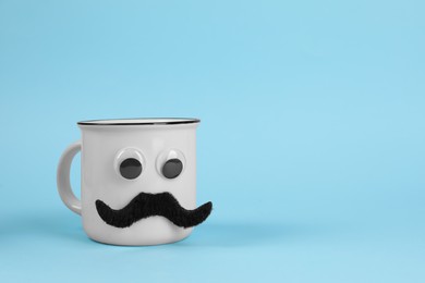 Man's face made of cup, fake mustache and decorative eyes on light blue background. Space for text