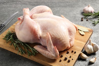 Photo of Fresh raw chicken with spices on grey textured table