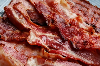 Slices of tasty fried bacon on plate, closeup