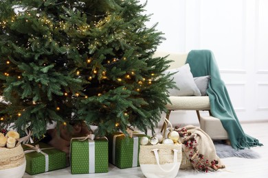 Many different gift boxes and firewood under Christmas tree indoors