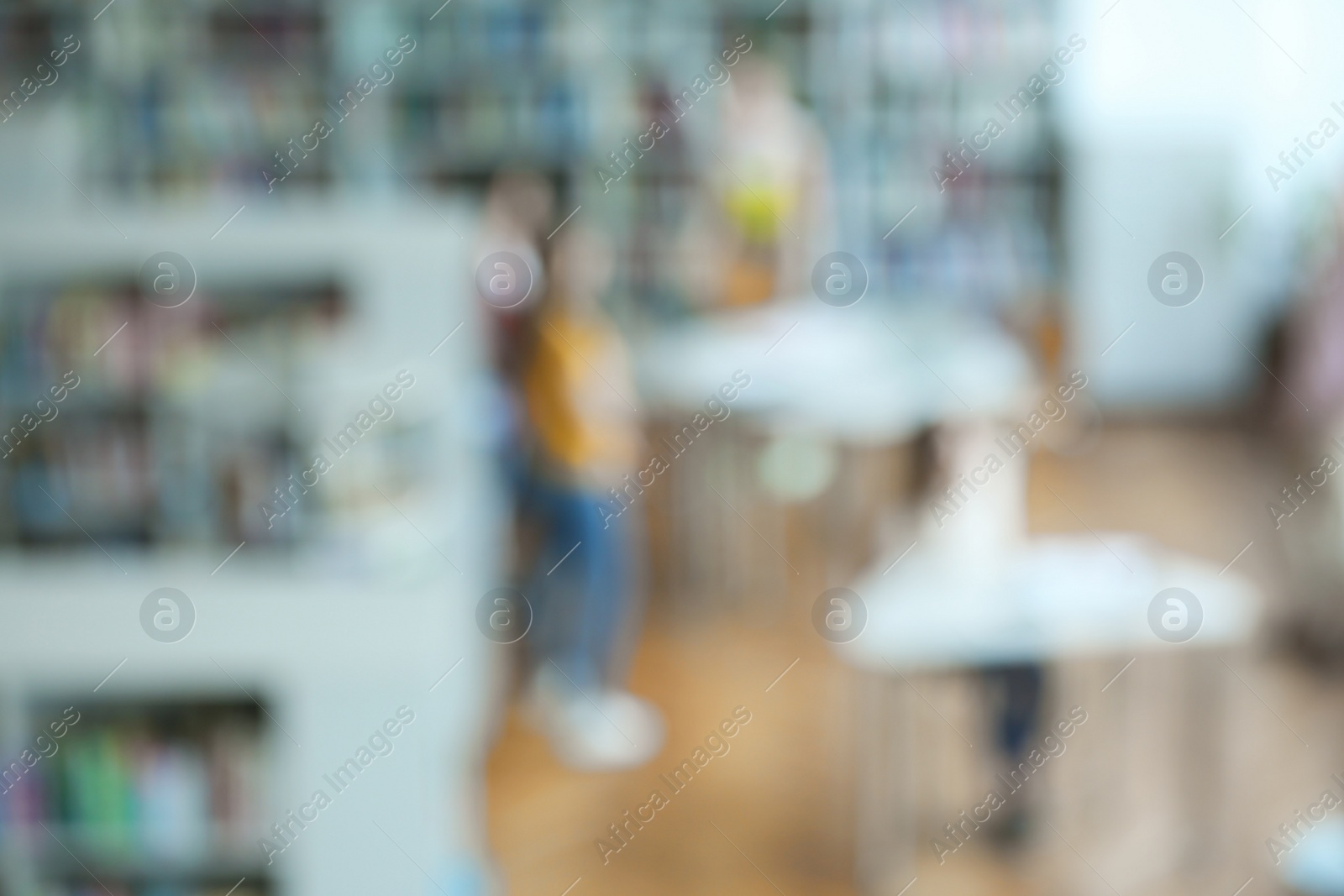 Photo of People and shelving units with books in library, blurred view