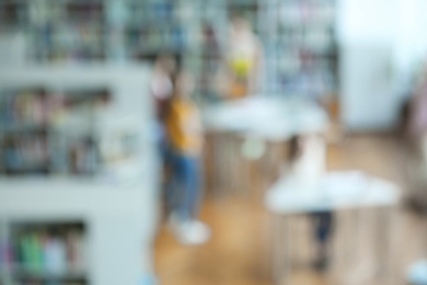 Photo of People and shelving units with books in library, blurred view