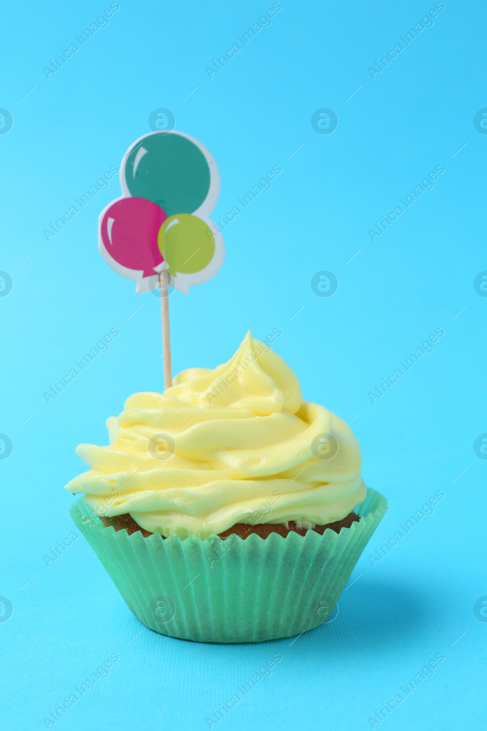 Photo of Delicious cupcake with bright cream and topper on light blue background