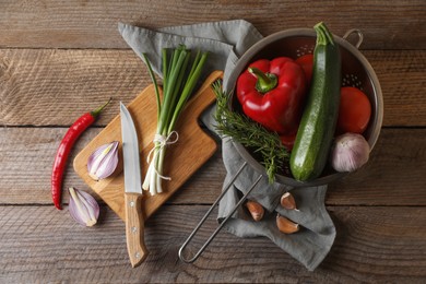 Photo of Cooking ratatouille. Vegetables, rosemary and knife on wooden table, flat lay