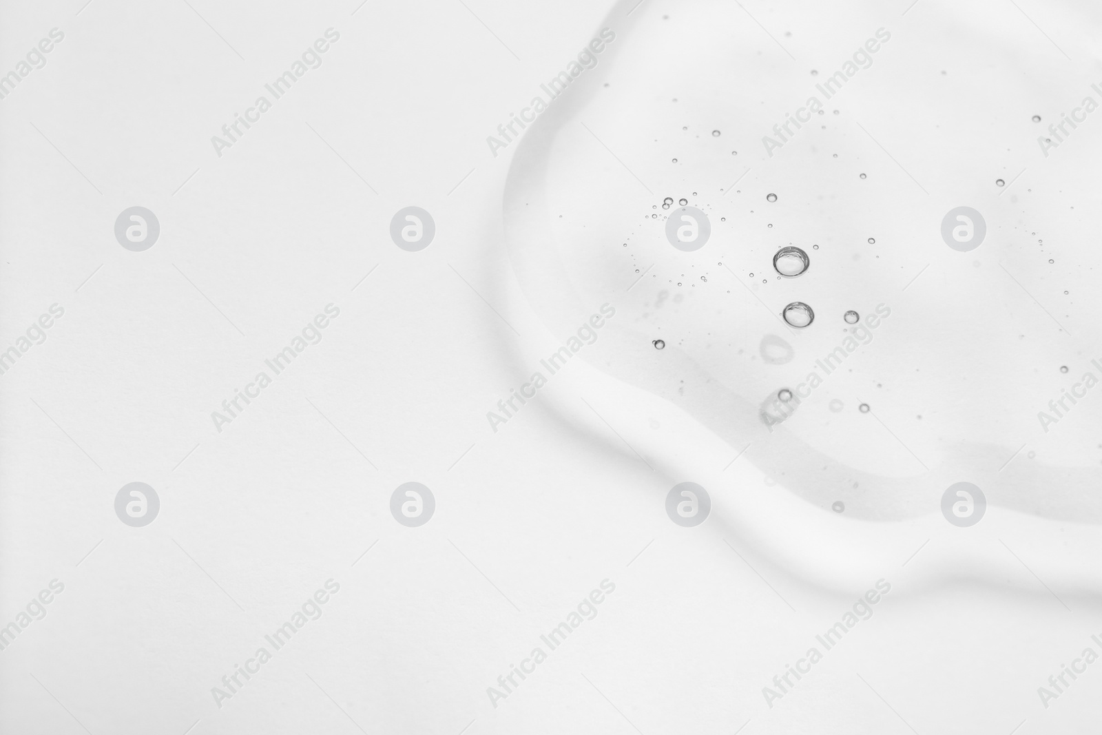 Photo of Sample of cosmetic oil on light surface, closeup. Space for text